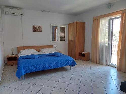 a bedroom with a bed with a blue blanket at Apartments Dora, with a beautiful view of the bay, near the sea and center in Vrboska