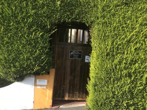 a wooden door in a hedge with a sign on it at Belton Apartments-Hedge Cottage in Hobart
