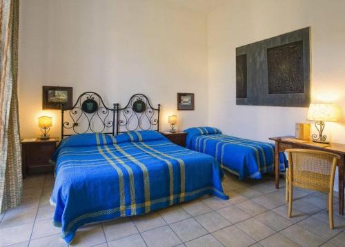 a bedroom with two beds with blue sheets and a table at Hotel Villa Maria Ischia Porto in Ischia