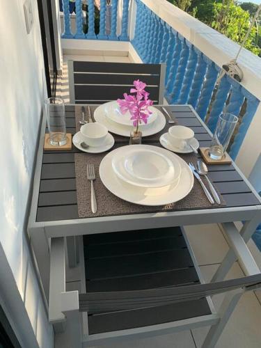 a table on a balcony with plates and a flower on it at Crystal Apartments Seychelles SeaView Ground Floor in Glacis