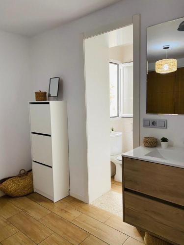 a bathroom with a sink and a toilet and a mirror at La casita de Lú in Casares