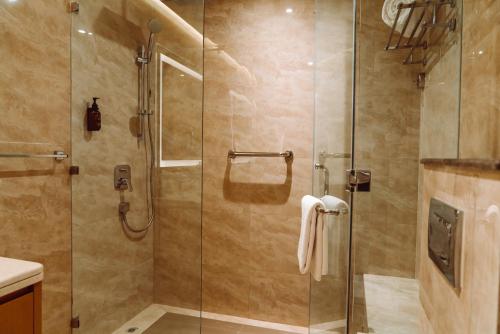 baño con ducha y puerta de cristal en HE Hotel Apartments by Gewan, en Dubái
