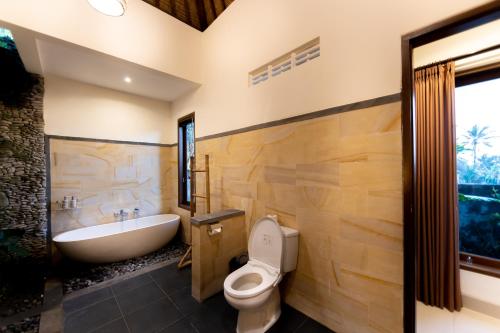 a bathroom with a tub and a toilet and a sink at Villa Natha in Ubud
