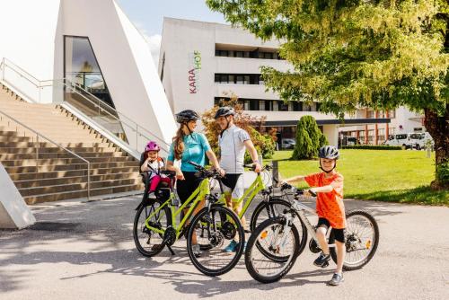 a family riding bikes in front of a building at Thermenhotel Karawankenhof in Villach