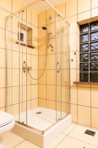 a shower with a glass door in a bathroom at Całoroczne Domki Cameo nad jeziorem żarnowieckim in Lubkowo