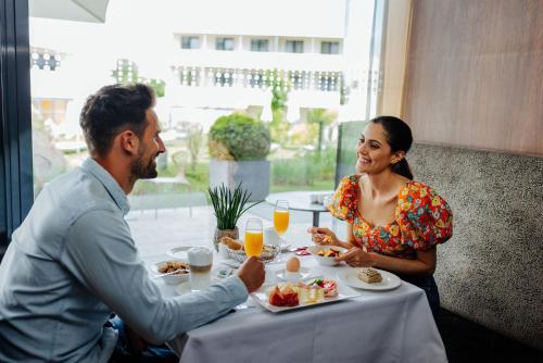 a man and woman sitting at a table eating food at Thermenhotel Karawankenhof in Villach