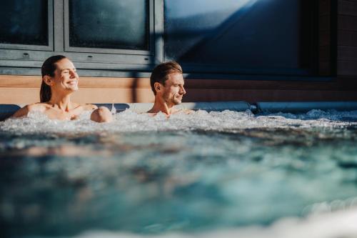 a man and woman sitting in a bathtub at Thermenhotel Karawankenhof in Villach
