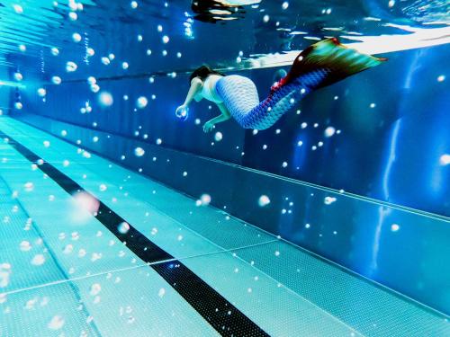 a woman is swimming in a swimming pool at Thermenhotel Karawankenhof in Villach