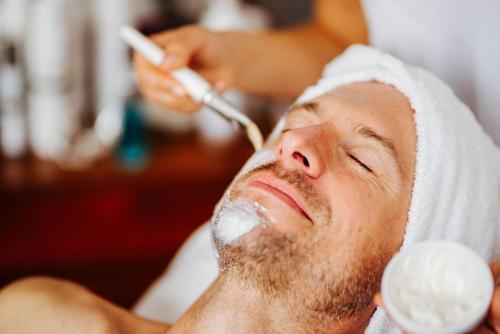 a man getting a shave at a barber shop at Thermenhotel Karawankenhof in Villach