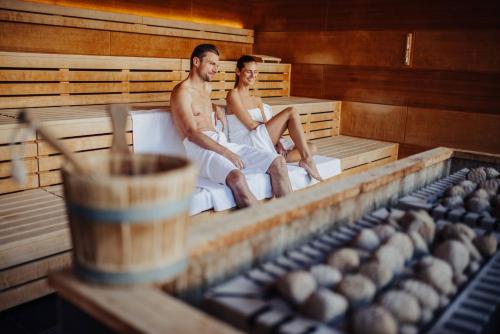 a man and a woman sitting in a sauna at Thermenhotel Karawankenhof in Villach