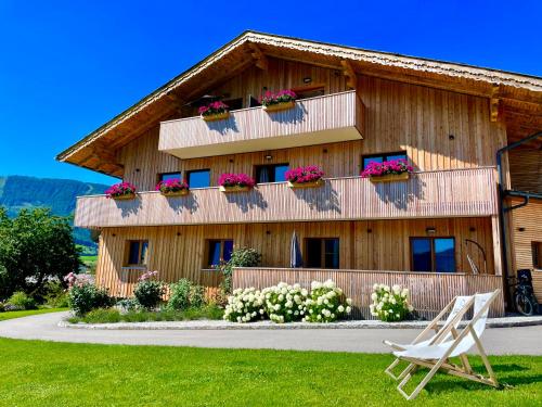Nachdemsee的住宿－KAINZLEITENHOF，一座带花盒和白色椅子的木制建筑