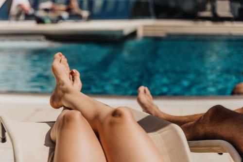 a woman laying on a chair next to a swimming pool at Thermenhotel Karawankenhof in Villach