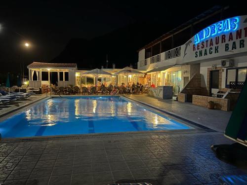 a large swimming pool in front of a hotel at night at Andreas Apartments in Kefalos