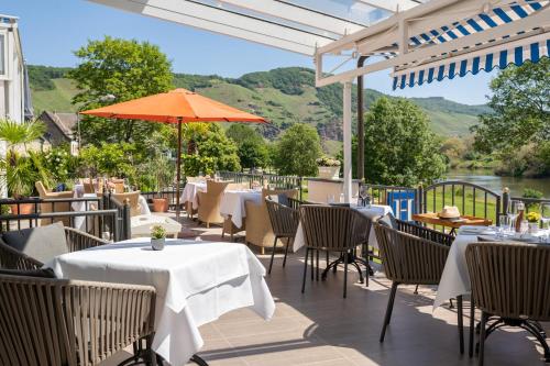 a patio with tables and chairs and an umbrella at Hotel Zur Traube in Ürzig