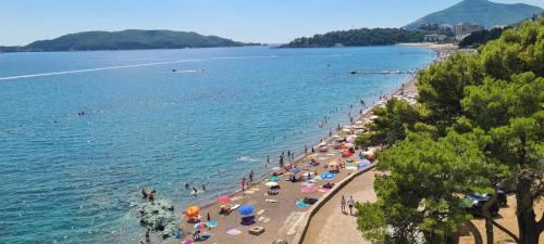 einen Strand mit Menschen und Sonnenschirmen im Wasser in der Unterkunft Jadran Dream in Rafailovici