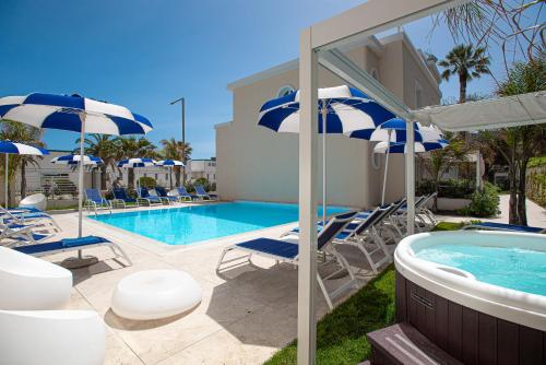 a swimming pool with blue and white umbrellas and chairs at Hotel Nautilus in Cagliari