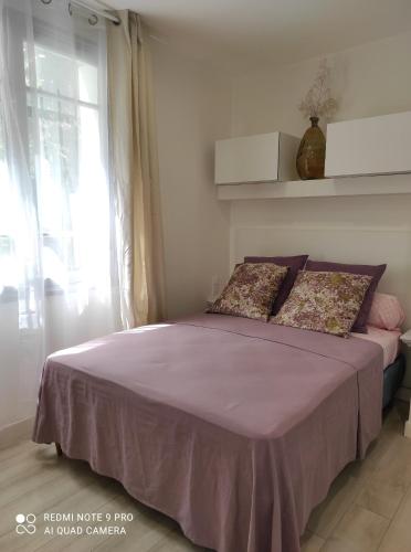 a bedroom with a bed with purple sheets and a window at Chambre accueillante à 2 mn du centre ville in Perpignan