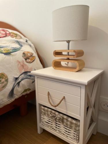 a table with a lamp on it next to a bed at Au Petit Brick - Cosy beachfront house in Maupertus-sur-Mer