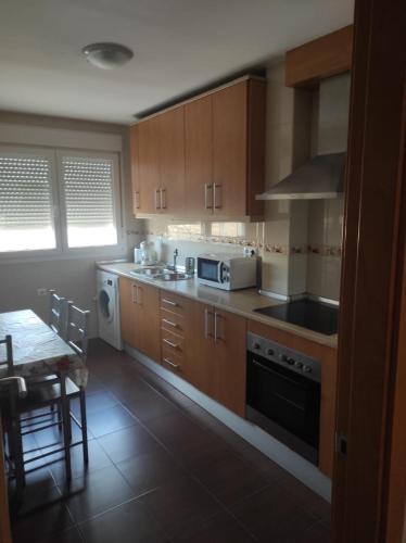a kitchen with wooden cabinets and a table with a microwave at Jesús Del Perdón in Manzanares