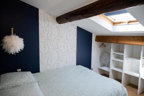 - une chambre avec un lit aux murs bleus et une lucarne dans l'établissement ColorZen - Confortable Lumineux Netflix - Appart Pézenas Centre, à Pézenas