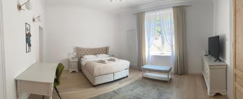a white bedroom with a bed and a television at Suite № 7 in Braşov