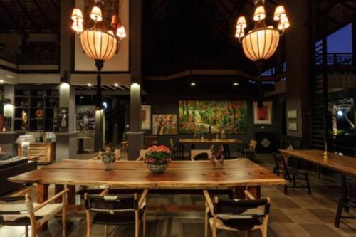 a dining room with a large wooden table and chairs at Baan Suan Residence เฮือนพักบ้านสวน in Chiang Mai