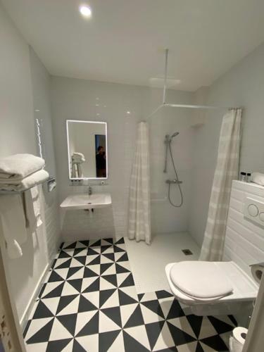 a bathroom with a black and white checkered floor at Hôtel Saint-Alban in Nézignan-lʼÉvêque