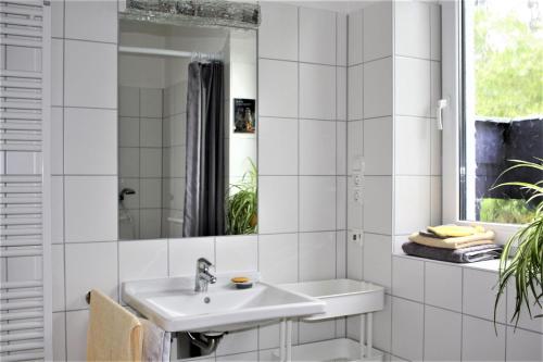 a white bathroom with a sink and a mirror at Das Blaue Haus - Ferienwohnung Schönherr in Kassel