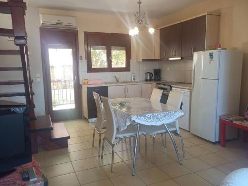 a kitchen with a table and chairs and a white refrigerator at ΜΕΖΟΝΕΤΑ in Nea Roda