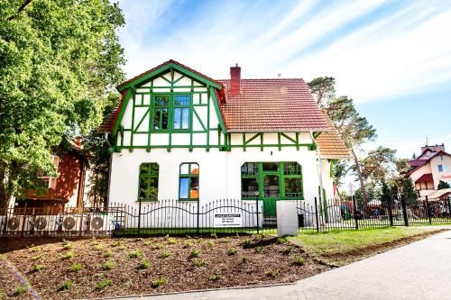 Biały i zielony dom z czarnym płotem w obiekcie Willa Kryniczanka w mieście Krynica Morska