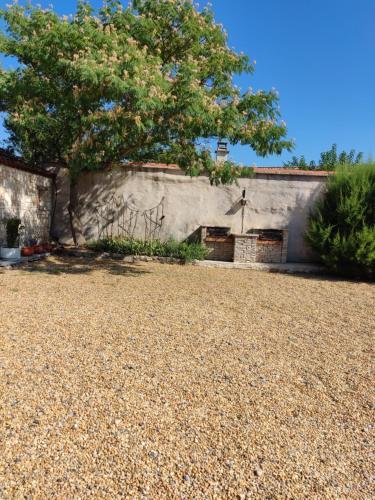 un mur en pierre avec un arbre dans une cour dans l'établissement Ardèche les cigales, studio laurier, à Grospierres