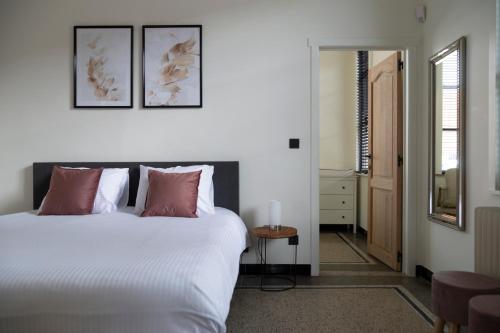 1 dormitorio con 1 cama blanca grande con almohadas rosas en Vakantievilla Leonie, en Lo-Reninge