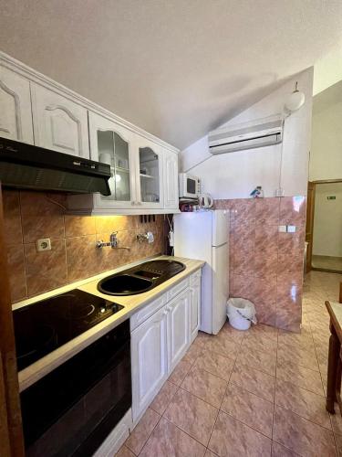 a kitchen with white cabinets and a sink and a refrigerator at Apartman Gorana with swimming pool in Jelsa