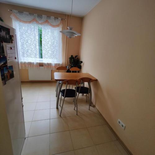 comedor con mesa, sillas y ventana en Dainai Apartament, en Šiauliai