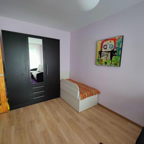 Dormitorio pequeño con cama y espejo en Dainai Apartament, en Šiauliai