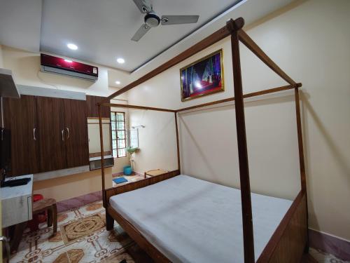 ein Schlafzimmer mit einem Himmelbett und einem TV an der Wand in der Unterkunft Monalisa Lodge in Vishnupur