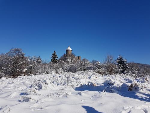 a snow covered hill with a building in the background at Galagonya Vendégház-Hegyvidéki szálláshely in Salgótarján