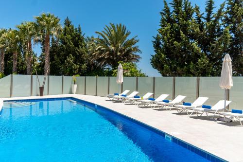 a swimming pool with lounge chairs and umbrellas at Villa Amelia by Ezoria Villas in Perivolia