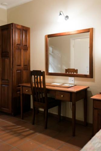 a wooden desk with a mirror and a chair at Tzaneen Country Lodge in Tzaneen