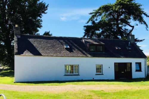 a white house with a black roof at Garbity Cottage in Fochabers