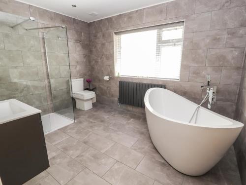 ein Badezimmer mit einer Badewanne, einem Waschbecken und einem WC in der Unterkunft Sea Breeze Cottage in Prestatyn