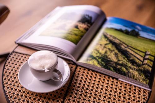 an open book with a coffee cup on a plate next to a book at OTTON-Charzykowy Bed&Restaurant in Chojnice