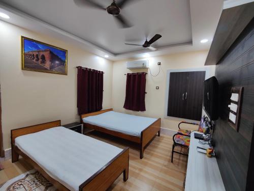 a hospital room with two beds and a tv at Monalisa Lodge in Vishnupur