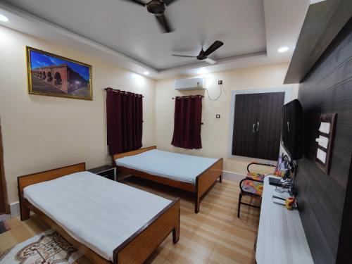 a room with two beds and a flat screen tv at Monalisa Lodge in Vishnupur