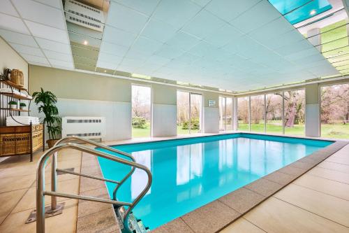 a swimming pool in a house with a ceiling at Hotel 't Kruisselt in De Lutte