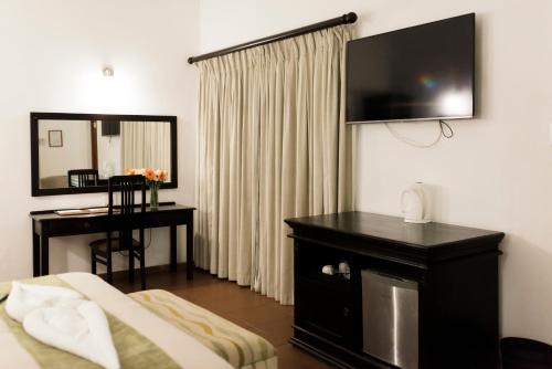 a hotel room with a bed and a desk and a television at Tzaneen Country Lodge in Tzaneen