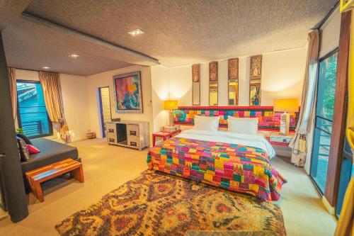 a bedroom with a colorful bed and a couch at Baan Suan Residence เฮือนพักบ้านสวน in Chiang Mai