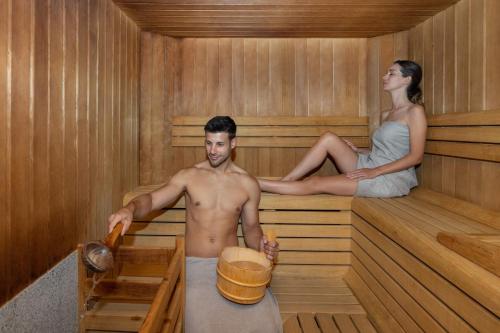 a man and a woman sitting in a sauna at Hotel Pejo in Peio Fonti
