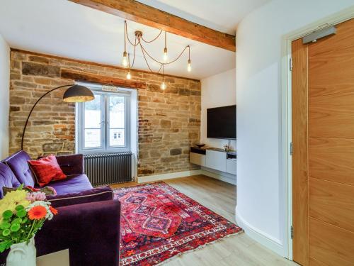 a living room with a purple couch and a brick wall at Up-Top Cottage in Holmfirth