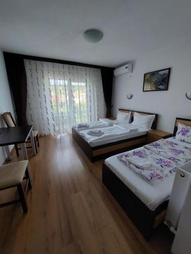 a bedroom with two beds and a table and a desk at Daiana Residence Turda in Turda